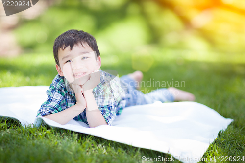 Image of Mixed Race Chinese and Caucasian Young Boy Relaxing Outside On T