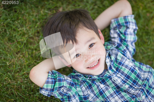 Image of Mixed Race Chinese and Caucasian Young Boy Relaxing On His Back 