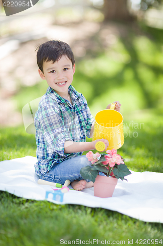 Image of Mixed Race Young Boy Watering His Potted Flowers Outside On The 