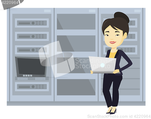 Image of Engineer working on laptop in network server room.
