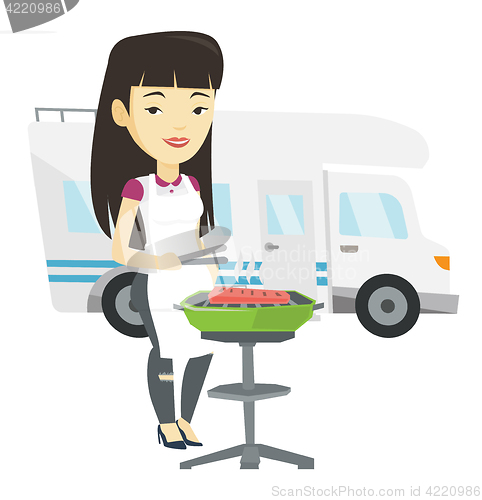 Image of Woman having barbecue in front of camper van.