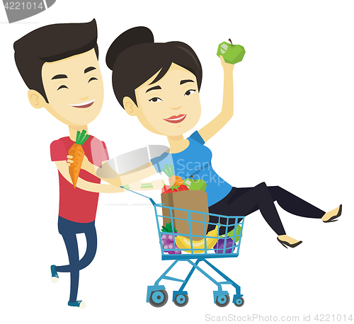 Image of Couple of friends riding by shopping trolley.