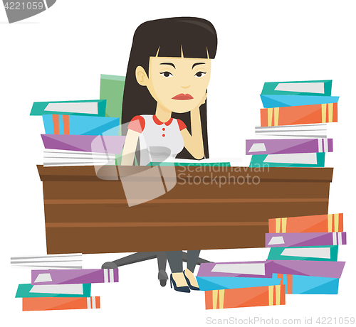 Image of Student sitting at the table with piles of books.