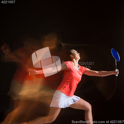 Image of Young woman playing badminton over black background