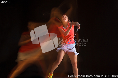 Image of Young woman playing badminton over black background