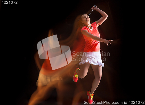 Image of Young woman playing badminton over black background