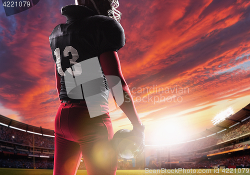 Image of American football player posing with ball on stadium background