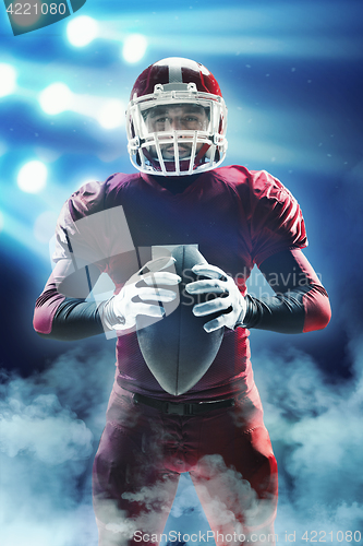 Image of American football player posing with ball on stadium background