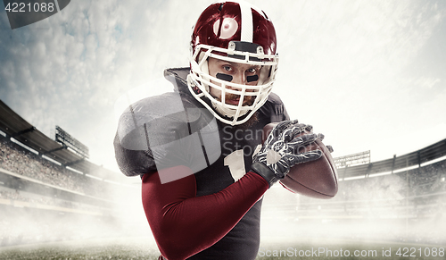 Image of American football player posing with ball on stadium background