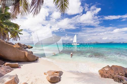 Image of Woman enjoying Anse Patates picture perfect beach on La Digue Island, Seychelles.