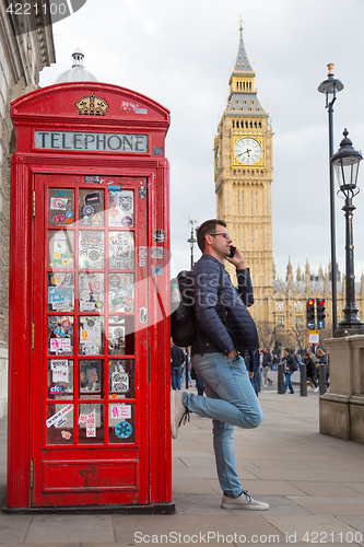 Image of Man talking on mobile phone, red telephone box and Big Ben. London, England