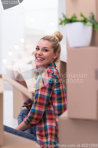 Image of woman with many cardboard boxes sitting on floor