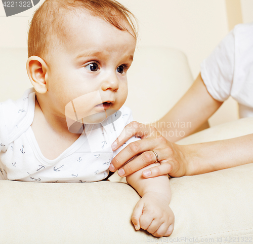 Image of little cute toddler baby boy playing on chair, mother insures holding hand, lifestyle people concept 