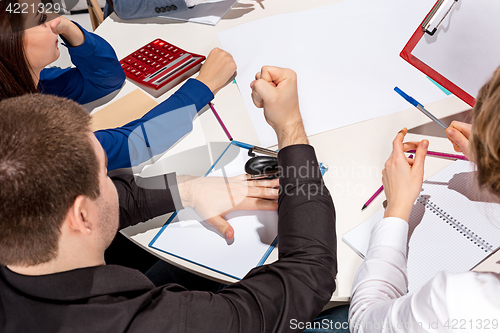 Image of Team sitting behind desk, checking reports, talking.