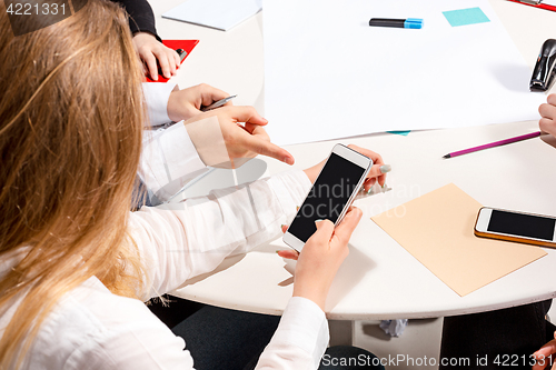 Image of The woman sitting behind desk, checking reports, talking.