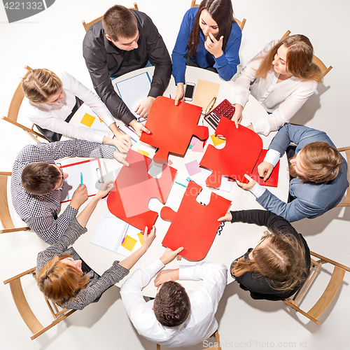 Image of Team sitting behind desk, checking reports, talking. Top View