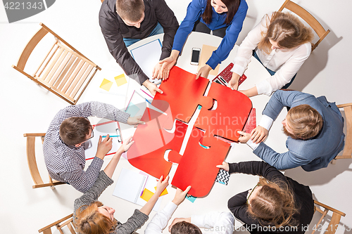 Image of Team sitting behind desk, checking reports, talking. Top View