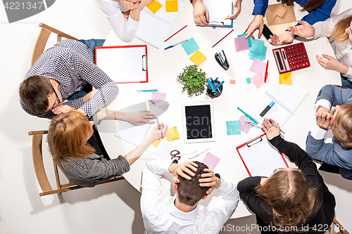 Image of Team sitting behind desk, checking reports, talking. Top View