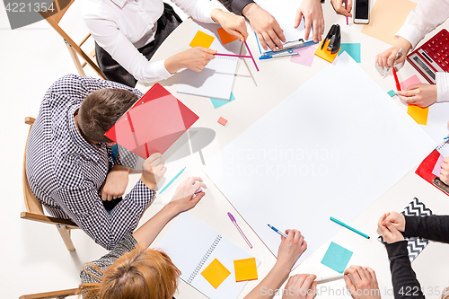 Image of Team sitting behind desk, checking reports, talking. Top View