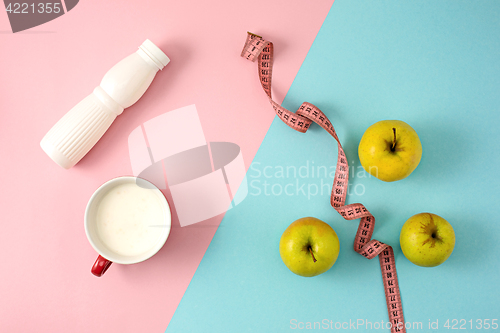 Image of The green apple and bottle of yogurt with measure tape