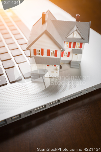 Image of Miniature House And Laptop Computer Resting on Desktop.