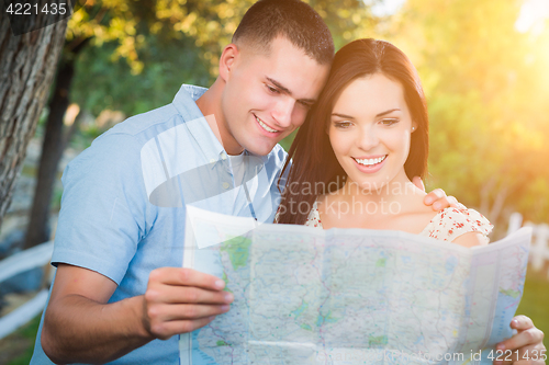 Image of Happy Mixed Race Couple Looking Over A Map Outside Together.