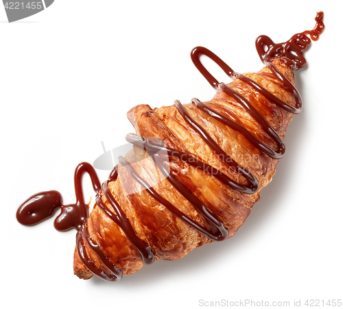 Image of freshly baked croissant decorated with chocolate sauce