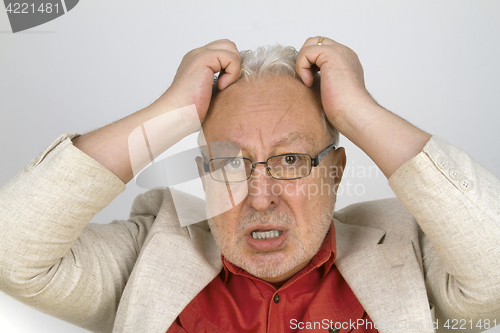 Image of White haired senior with glasses tearing his hair