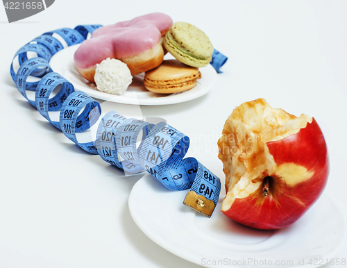 Image of new real diet concept, question sign in shape of measurment tape between red apple and donut isolated on white 
