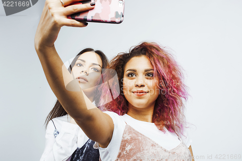 Image of lifestyle people concept: two pretty stylish modern hipster teen girl having fun together, diverse nation mixed races, happy smiling making selfie 