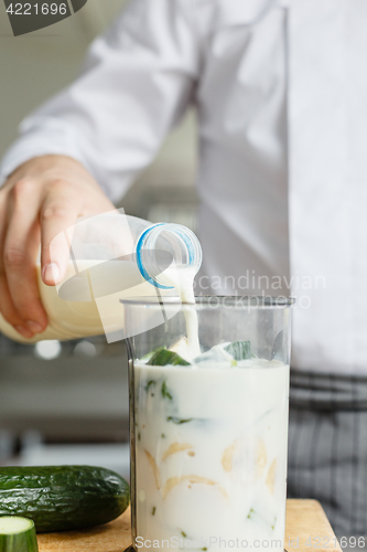 Image of Male pouring milk while preparing smoothie