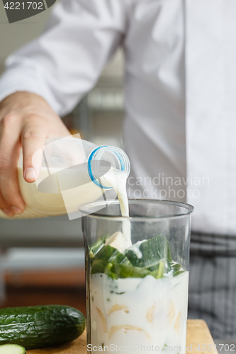 Image of Male pouring milk while preparing smoothie