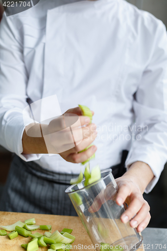 Image of Crop hands pouring cut celery in container