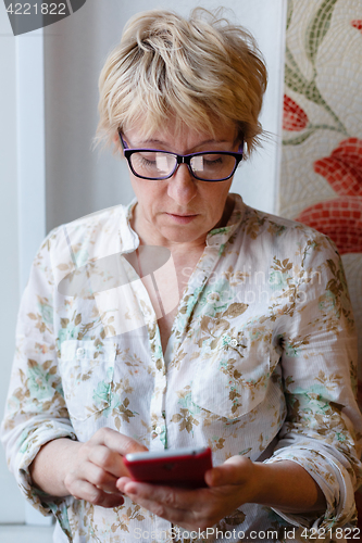 Image of Mature woman in glasses using device