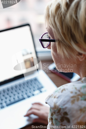 Image of Back view of woman using laptop