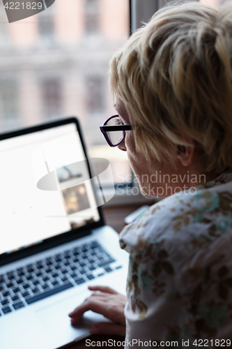 Image of Back view of woman using laptop