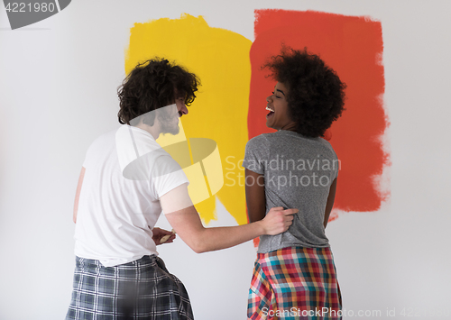 Image of multiethnic couple painting interior wall