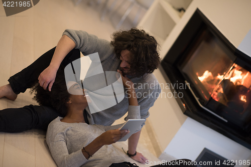 Image of multiethnic couple using tablet computer on the floor