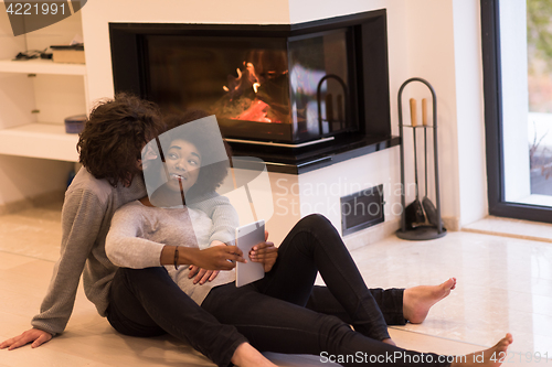 Image of multiethnic couple using tablet computer on the floor