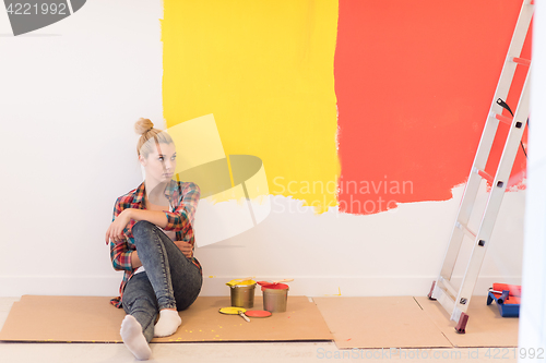 Image of young female painter sitting on floor