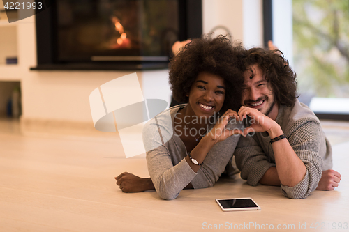 Image of multiethnic couple showing a heart with their hands on the floor