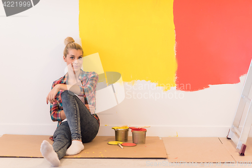 Image of young female painter sitting on floor