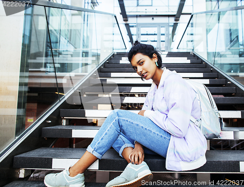 Image of young cute indian girl at university building sitting on stairs 