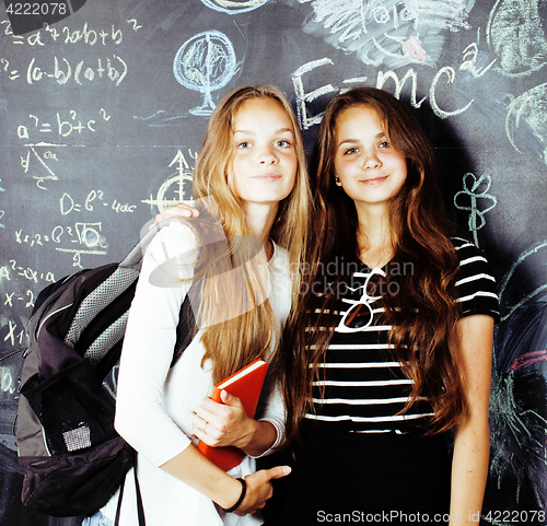 Image of back to school after summer vacations, two teen real girls in classroom with blackboard painted together, lifestyle people concept close up