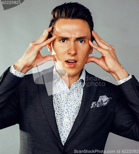 Image of young pretty business man standing on grey background, modern hairstyle, gesturing emotional