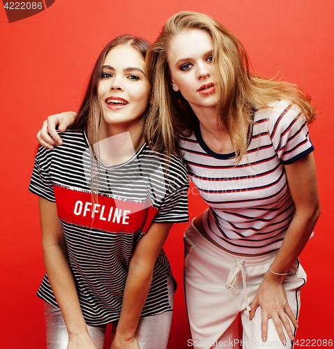 Image of two best friends teenage girls together having fun, posing emotional on red background, besties happy smiling, lifestyle people concept close up