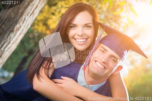 Image of Happy Male Graduate in Cap and Gown and Pretty Girl Celebrate Ou