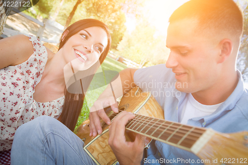 Image of Happy Mixed Race Couple at the Park Playing Guitar and Singing S