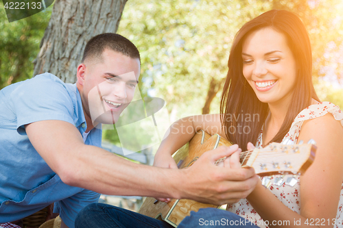 Image of Handsome Young Man Teaching Mixed Race Girl to Play Guitar at th