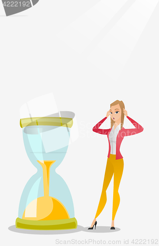 Image of Desperate business woman looking at hourglass.